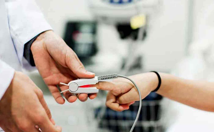 Doctor using pulse oximeter on patient